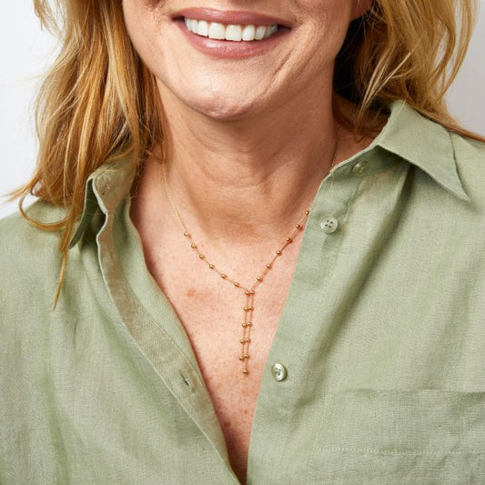 model wearing Ball Chain Lariat Gold Long Necklace, featuring a sleek and stylish long gold chain with interlinked ball details, designed as a lariat for added elegance and versatility, perfect for complementing any outfit with a modern and luxurious touch.