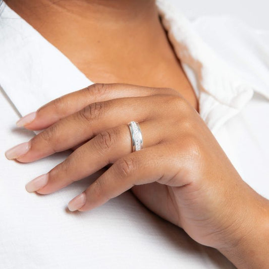 Close-up of a hand wearing a Cubic Zirconia Silver Spinner Ring on a white background