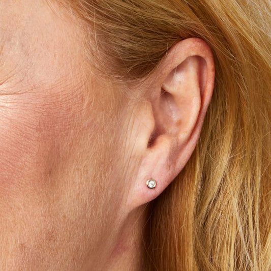 Model wearing Rounded Bezel Diamond Stud Earrings in 9ct Gold ge2478, featuring classic bezel-set diamonds in polished 9ct gold, perfect for adding timeless elegance and sophistication to any outfit.