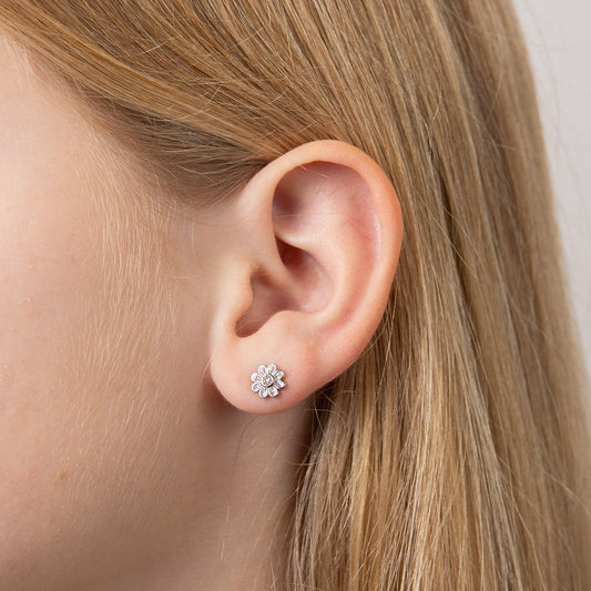 Child model wearing silver and pink flower stud earrings for children, girls, and babies, featuring a delicate floral design with a polished silver finish and soft pink enamel accents, perfect for adding charm and elegance to a young jewelry collection.