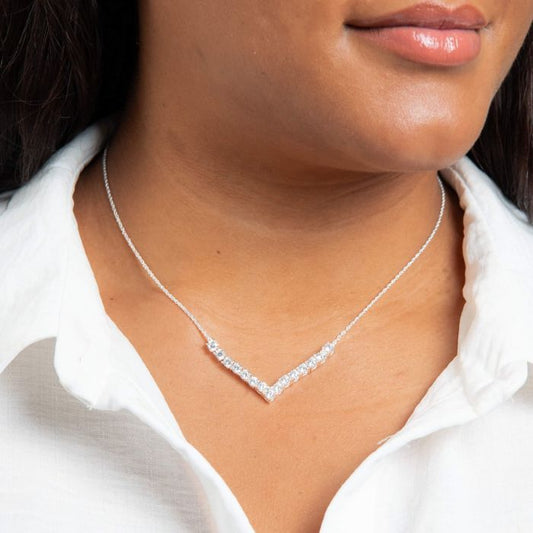 cubic zirconia necklace in V-shaped silver necklace worn by a person with a white shirt