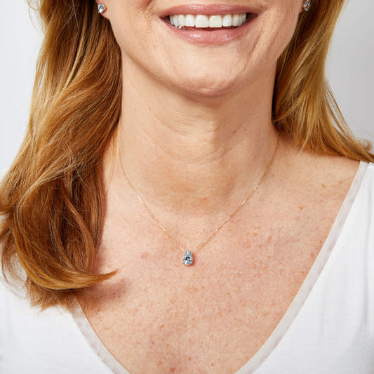 close up of woman neck wearing Pear Fancy Cut Topaz Gold Stud Earrings on ear and necklace around neck as a set on light background