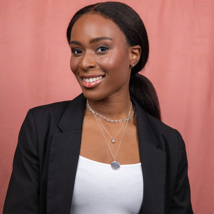 Woman wearing a black blazer and white top with style example layered Solid Teardrop Necklace silver. layered necklaces against a pink background