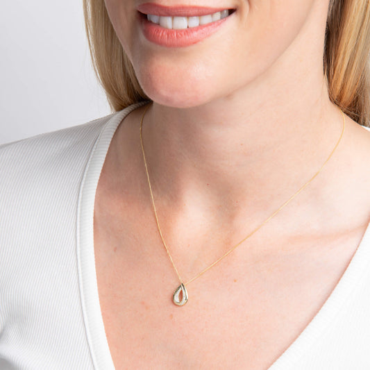woman wearing Gold Cut Out Diamond Teardrop Pendant necklace with white top on white background