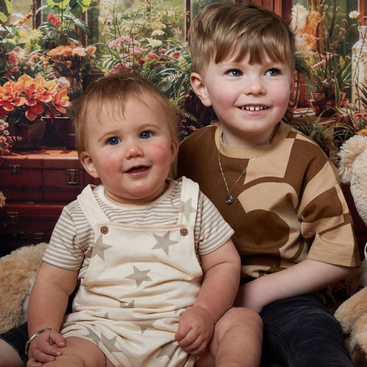 Toddler and young child sitting together wearing jewelry from SilverageLondon.co.uk Little Ones collection, showcasing delicate and stylish pieces designed for children, perfect for special occasions and everyday wear.