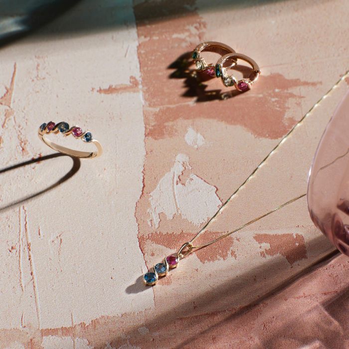 showcase of gold jewelry set of ring necklace and earrings on pink marble background 