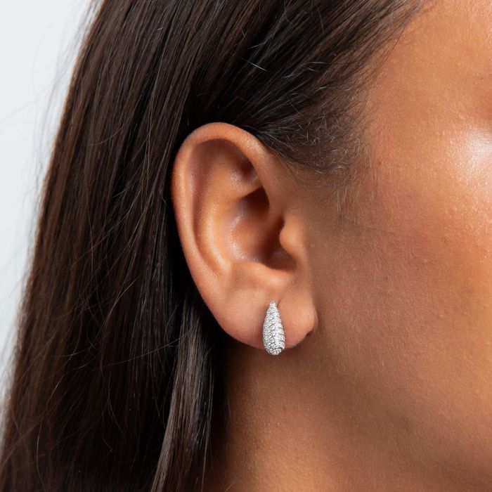 Close-up of an ear wearing a Channel Set Silver Droplet Stud Earrings with dark hair and skin background