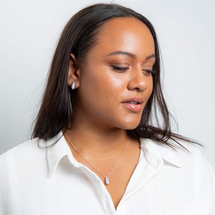 Woman wearing Channel Set Droplet Stud Earrings silver and an white shirt against a plain background