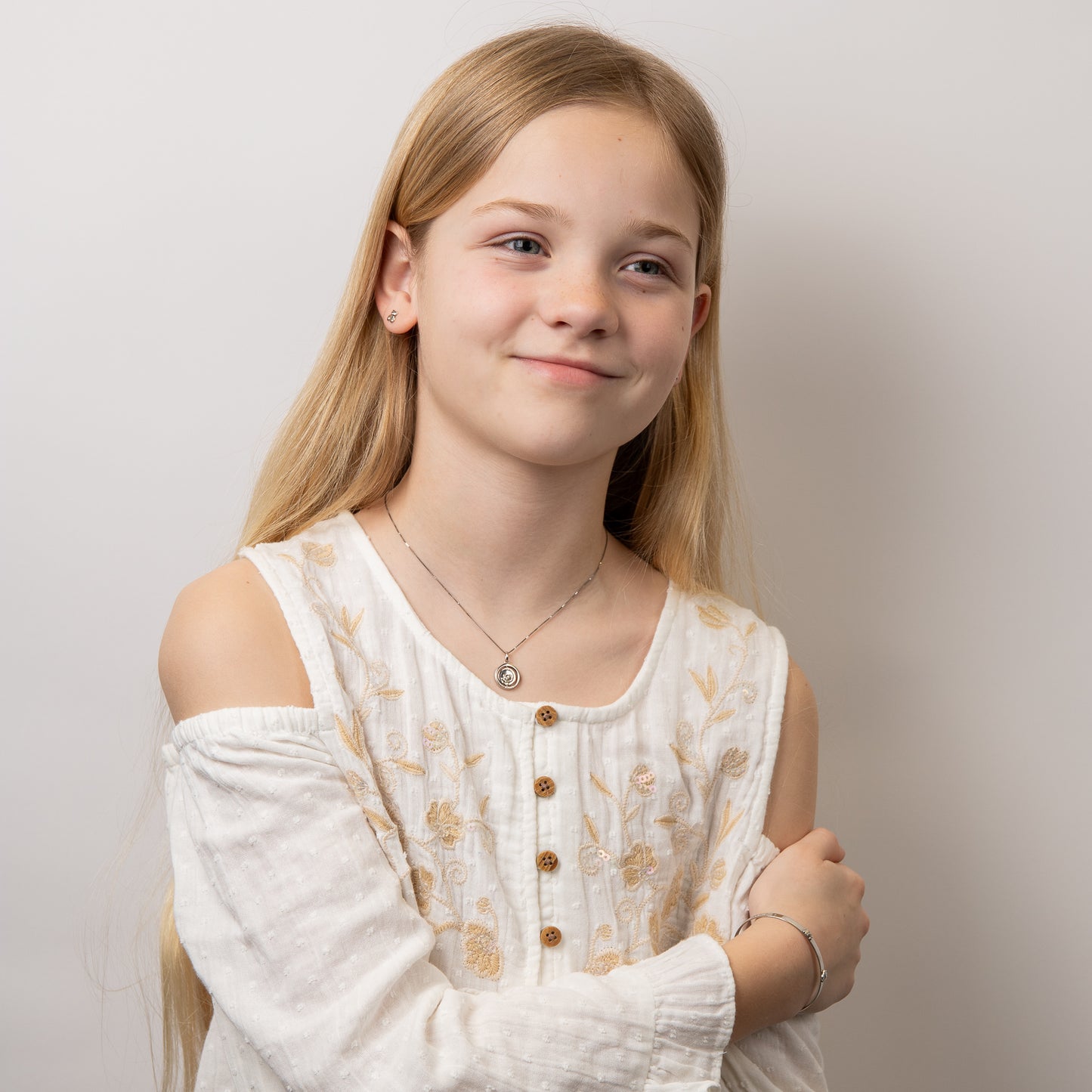 Child model wearing silver teddy bear jewelry set, featuring an adorable teddy bear pendant and matching stud earrings crafted in polished silver with sparkling diamond accents, perfect for adding charm and elegance to a young jewellery collection.