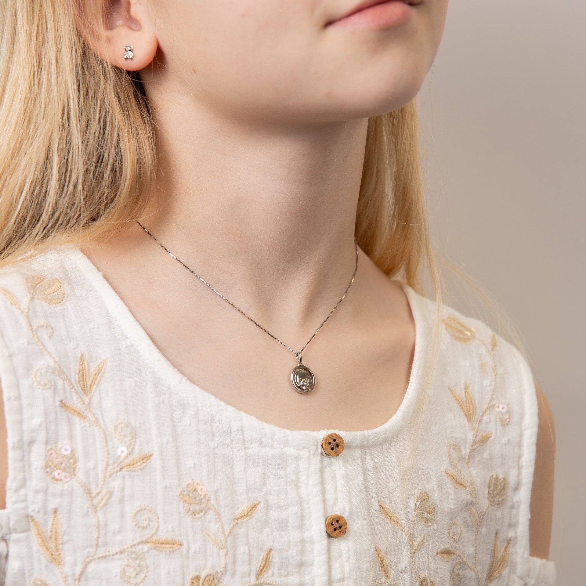 close up of Child wearing silver teddy bear necklace, featuring a charming teddy bear pendant crafted in polished sterling silver, perfect for adding a touch of sweetness and elegance to a young jewellery collection.