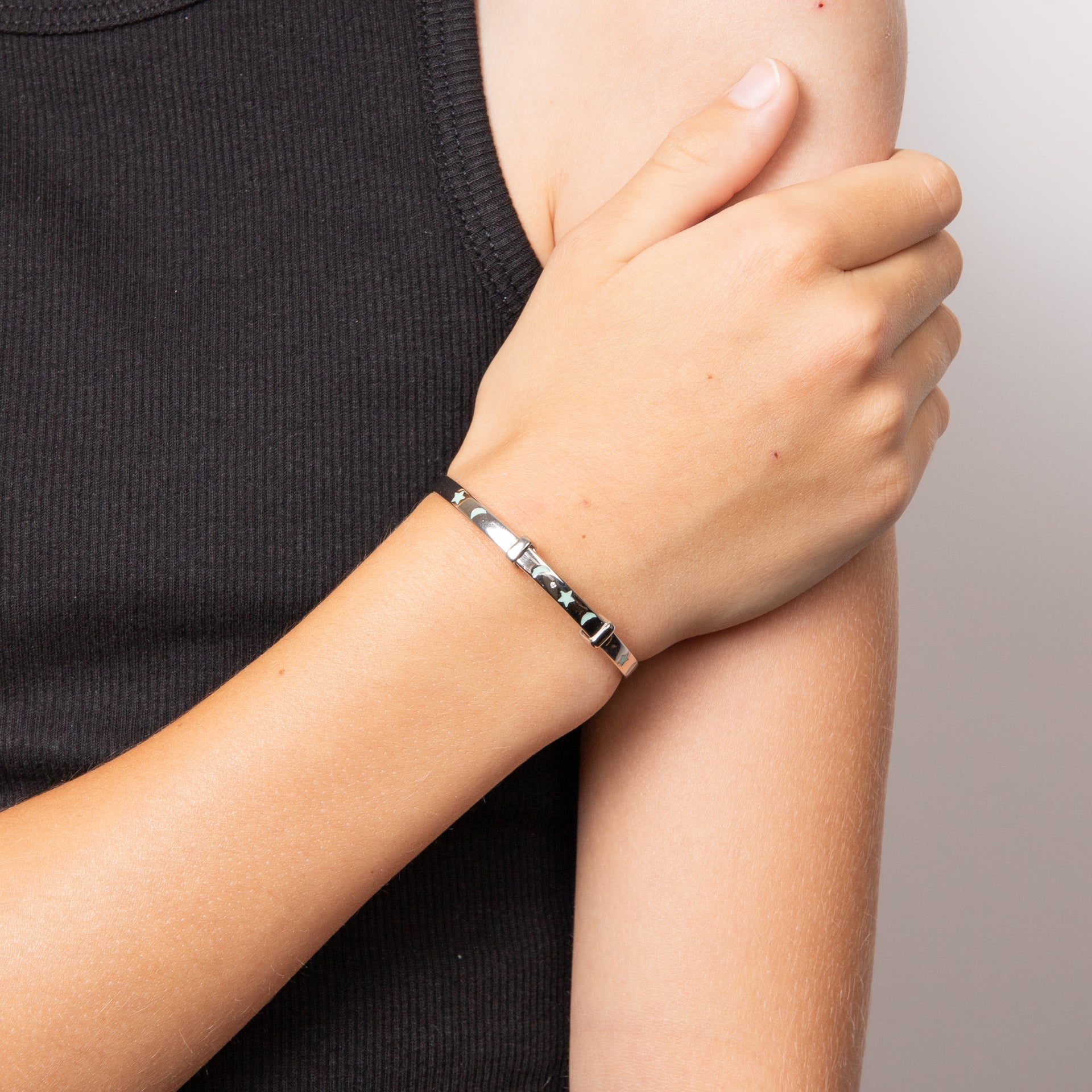Child arm wearing Glow in the Dark Star and Moon Silver Bangle with Diamond, featuring a magical celestial design with glow-in-the-dark star and moon details, a sparkling diamond accent, and a polished silver finish, perfect as a whimsical and elegant jewellery piece for children.
