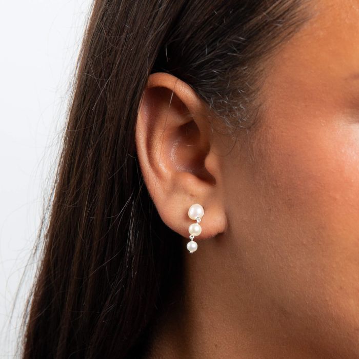 Close-up of an ear wearing Gradient Fresh water Pearl Drop Earrings with a plain background