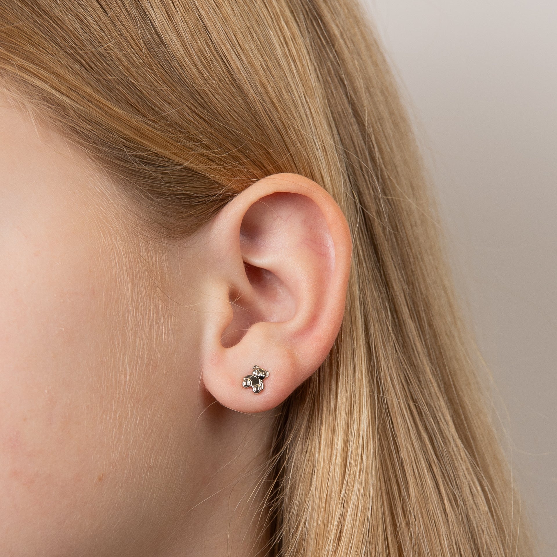 Child model wearing children's and babies' silver teddy bear stud earrings with diamond nose, featuring an adorable teddy bear design crafted in polished silver with a sparkling diamond accent, perfect for adding charm and elegance to a young jewelry collection.