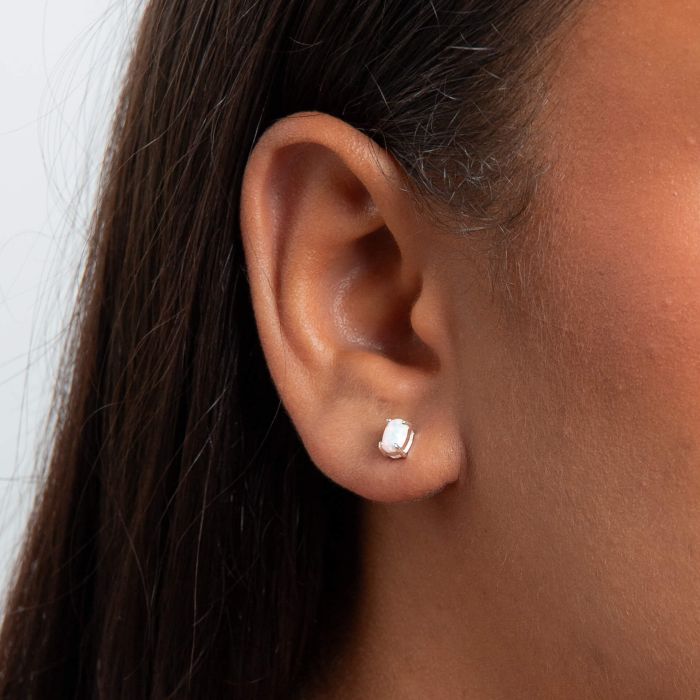 Close-up of an ear wearing a Oval Opal silver Stud Earrings on a neutral background