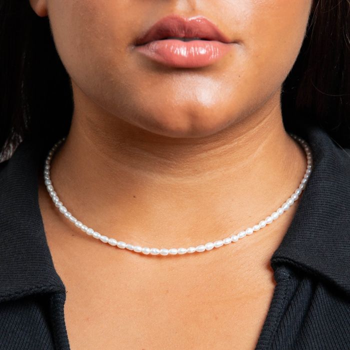 Close-up of a person  wearing a pearl seed necklace choker style with a blurred background