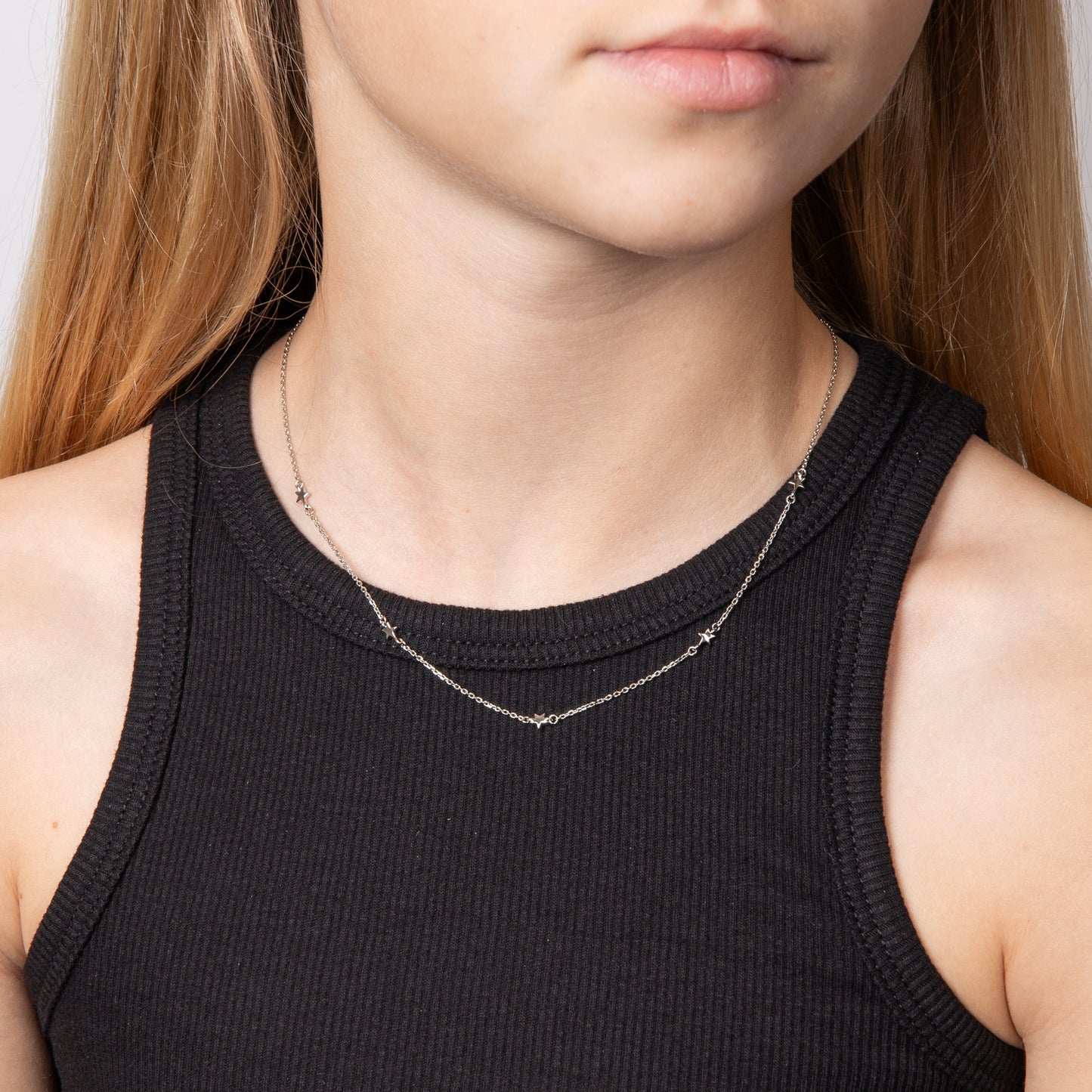 Child wearing a silver necklace designed for children close up, featuring a delicate and elegant design, perfect as a timeless keepsake or everyday accessory for young jewellery lovers.
