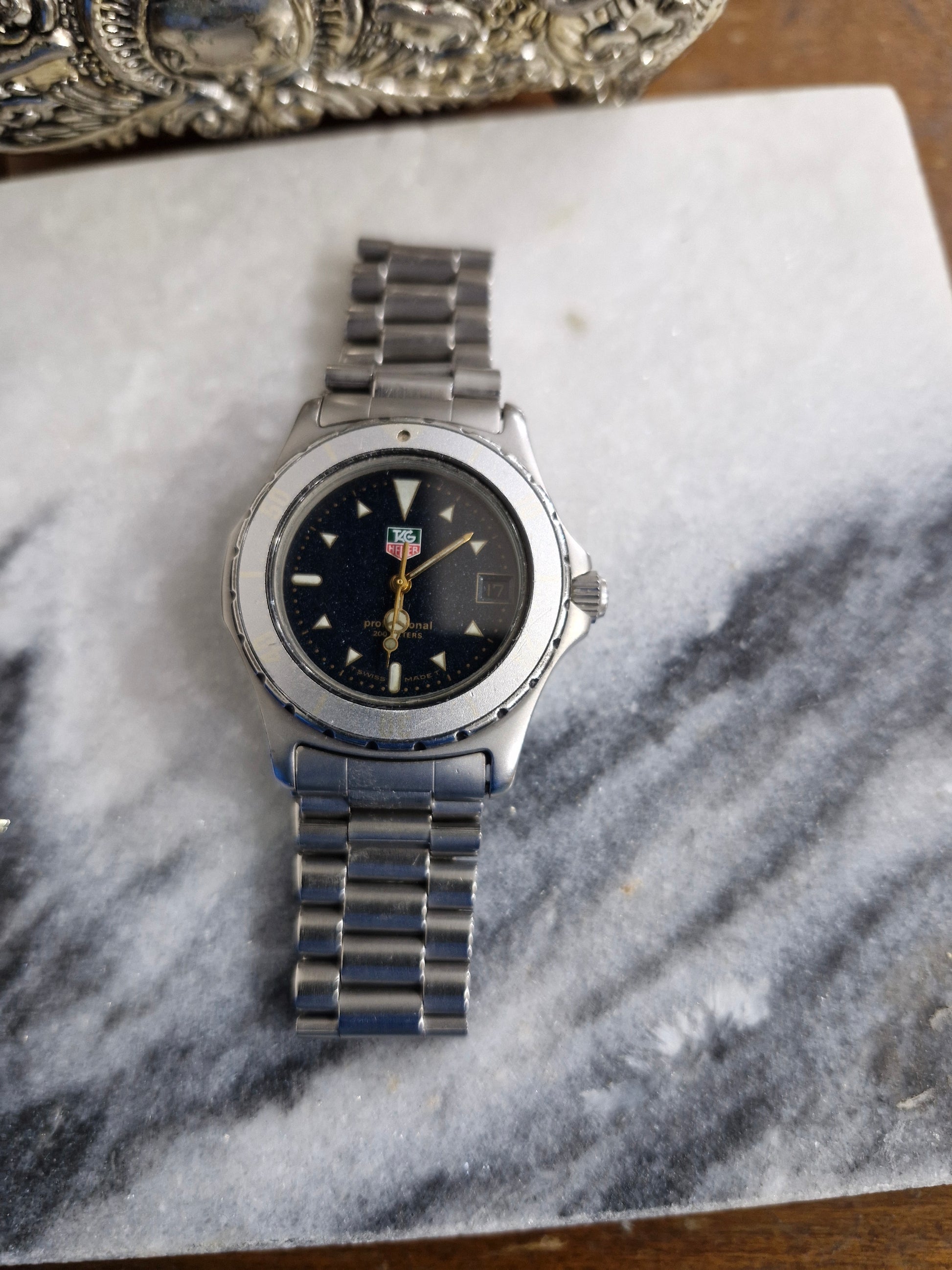 Tag Heuer 2000 Professional quartz dive watch from the 1990s, featuring a blue bezel, blue sparkle dial, and original oyster bracelet. On marble background 