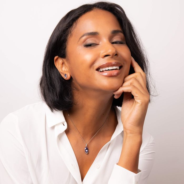 Model wearing Tanzanite Purple Crystal Necklace p5328m paired with Tanzanite Purple Crystal Earrings e6379m, featuring a matching set with vibrant tanzanite-colored crystals and sparkling cubic zirconia accents, perfect for elegant and coordinated jewelry styling.