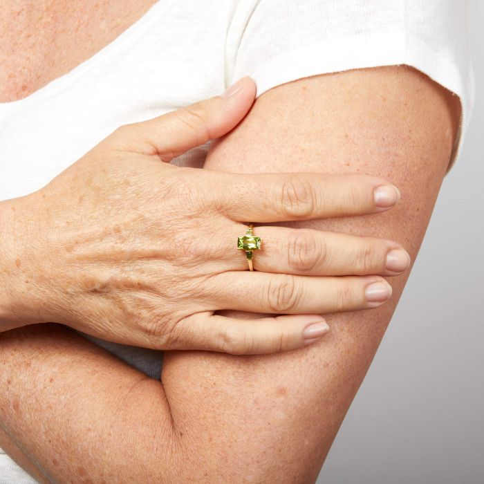  Model wearing Trilogy Peridot Ring in 9ct Gold gr637g, featuring three vibrant green peridot gemstones set in polished 9ct gold, symbolizing past, present, and future, perfect for adding elegance and meaning to any outfit.