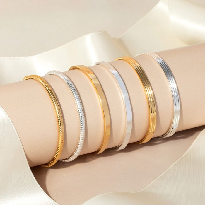 Set of gold and silver bracelets on a beige fabric background