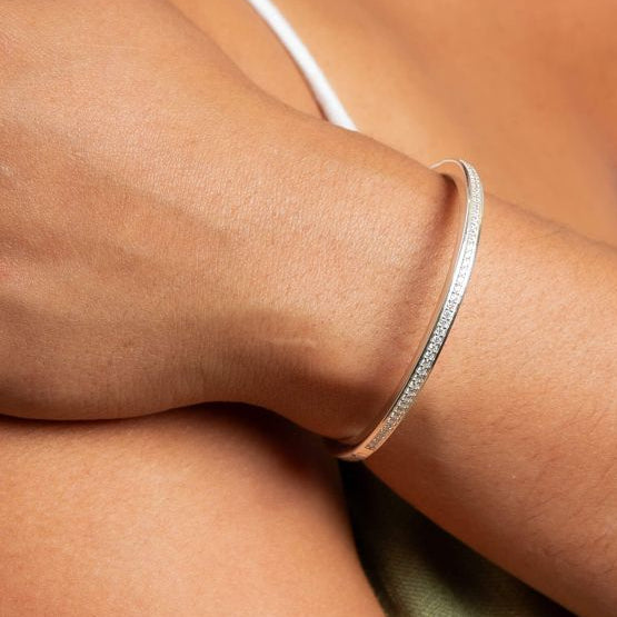Silver Hinged Bangle with Cubic Zirconia on a person's wrist with a blurred background