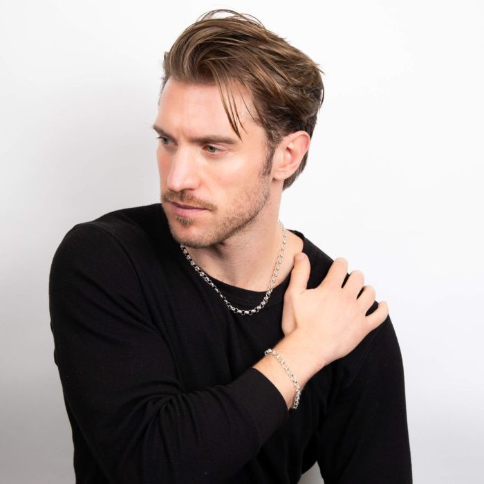 Man wearing a black shirt and Belcher silver Chain Necklace and bracelet against a white background