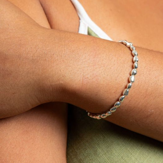 Organic Bead Stretch silver Bracelet on a person's wrist with a neutral background