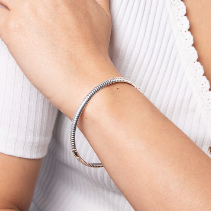 Silver bracelet on a person's wrist with a white background