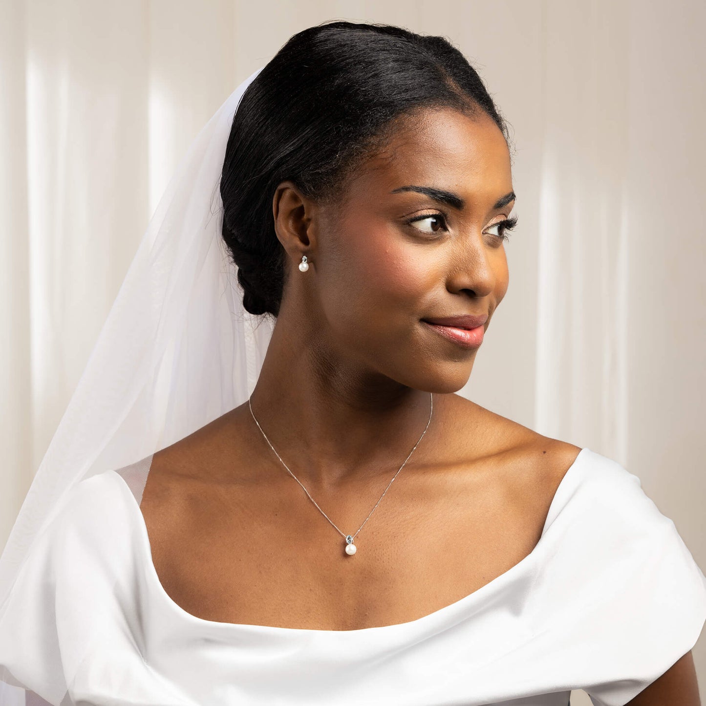 woman wearing bridal outfit with 9ct White Gold Freshwater Pearl & Sky Blue Topaz Pendant necklace and earrings set against white light background