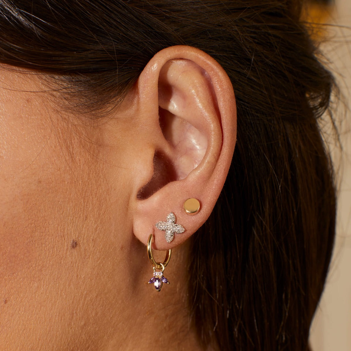 close up of ear stacked with hoop and two stud one circle and one flower paved stud earrings