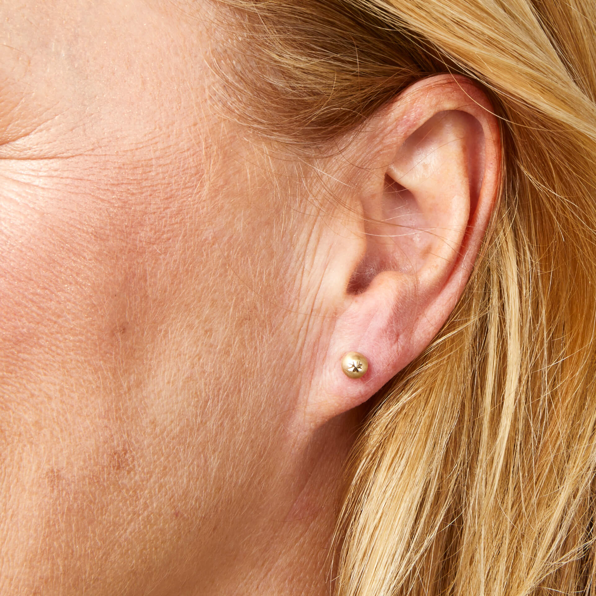 Close up of ear wearing Starburst Detail Ball Gold Stud Earrings 