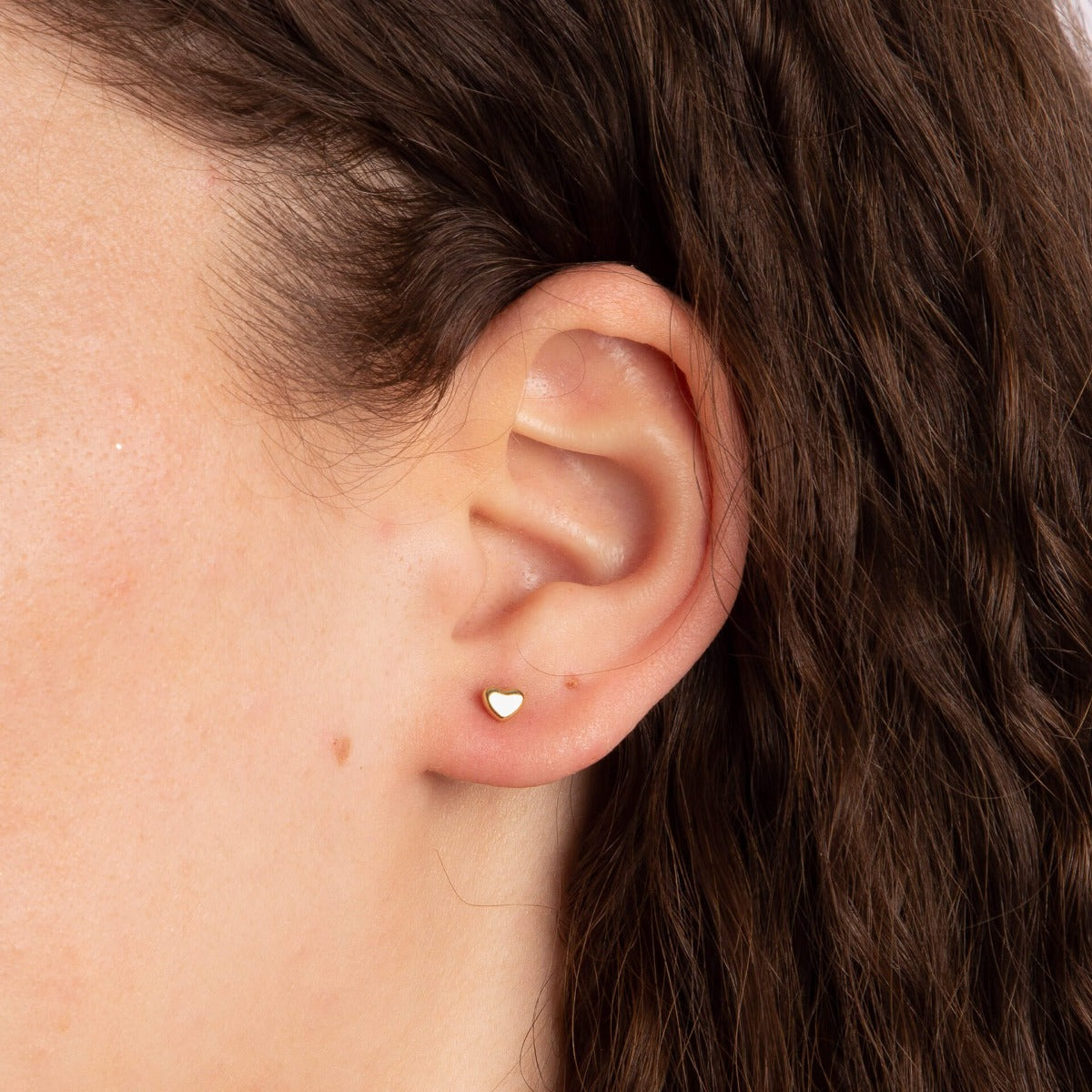 close up of ear wearing small Gold heart stud earring 