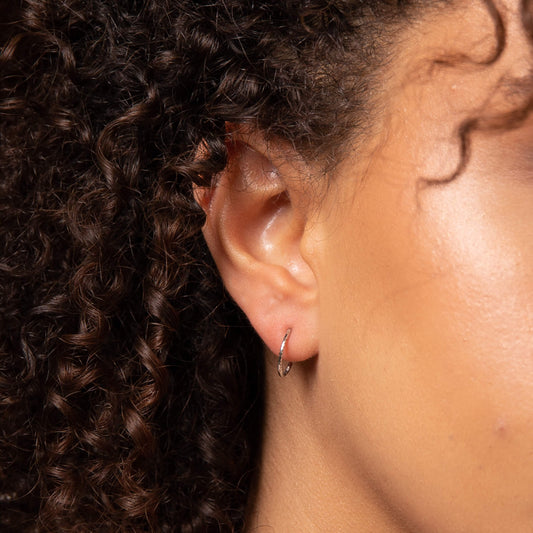 close up of ear with gold slim hoop earring 