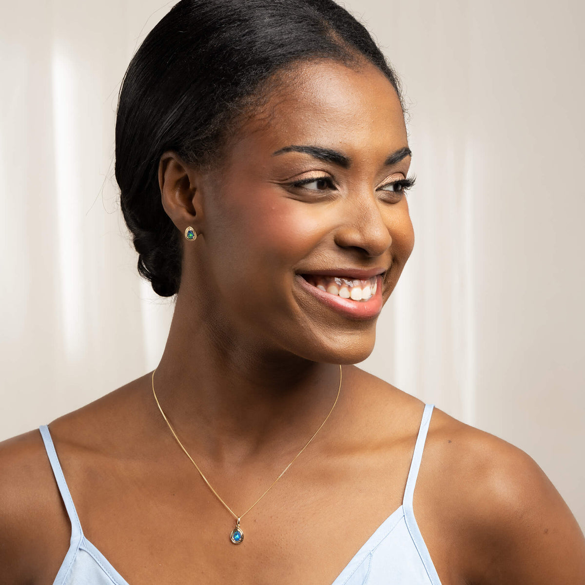 close up woman 9ct Gold Australian Blue Opal Doublet Teardrop Stud Earrings and necklace set with blue spaghetti strap top 