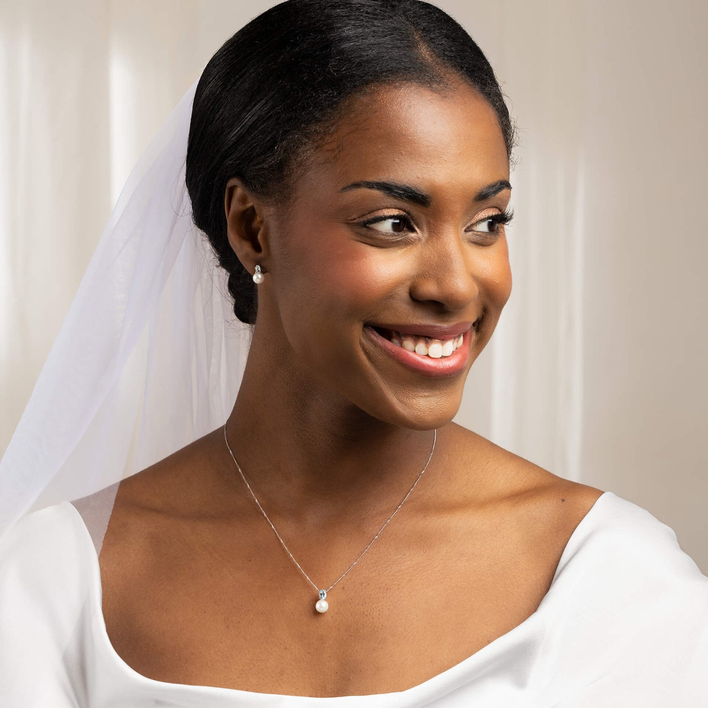 close up woman dressed as bride wearing  9ct Gold Freshwater Pearl & Sky Blue Topaz Pendant necklace and earrings set smiling 