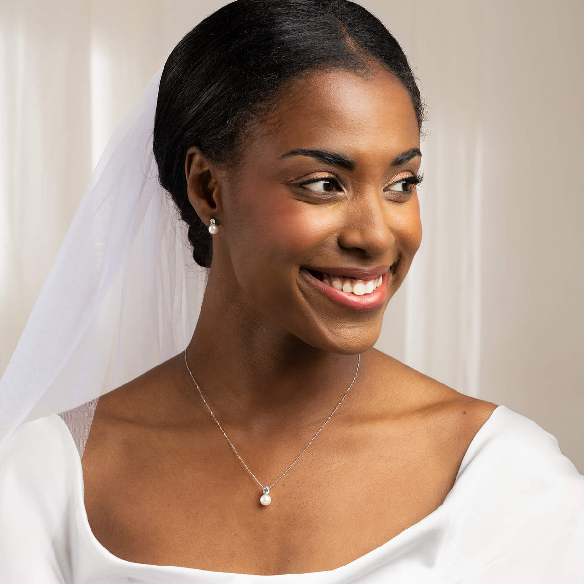 close up woman dressed as bride wearing  9ct Gold Freshwater Pearl & Sky Blue Topaz Pendant necklace and earrings set smiling 