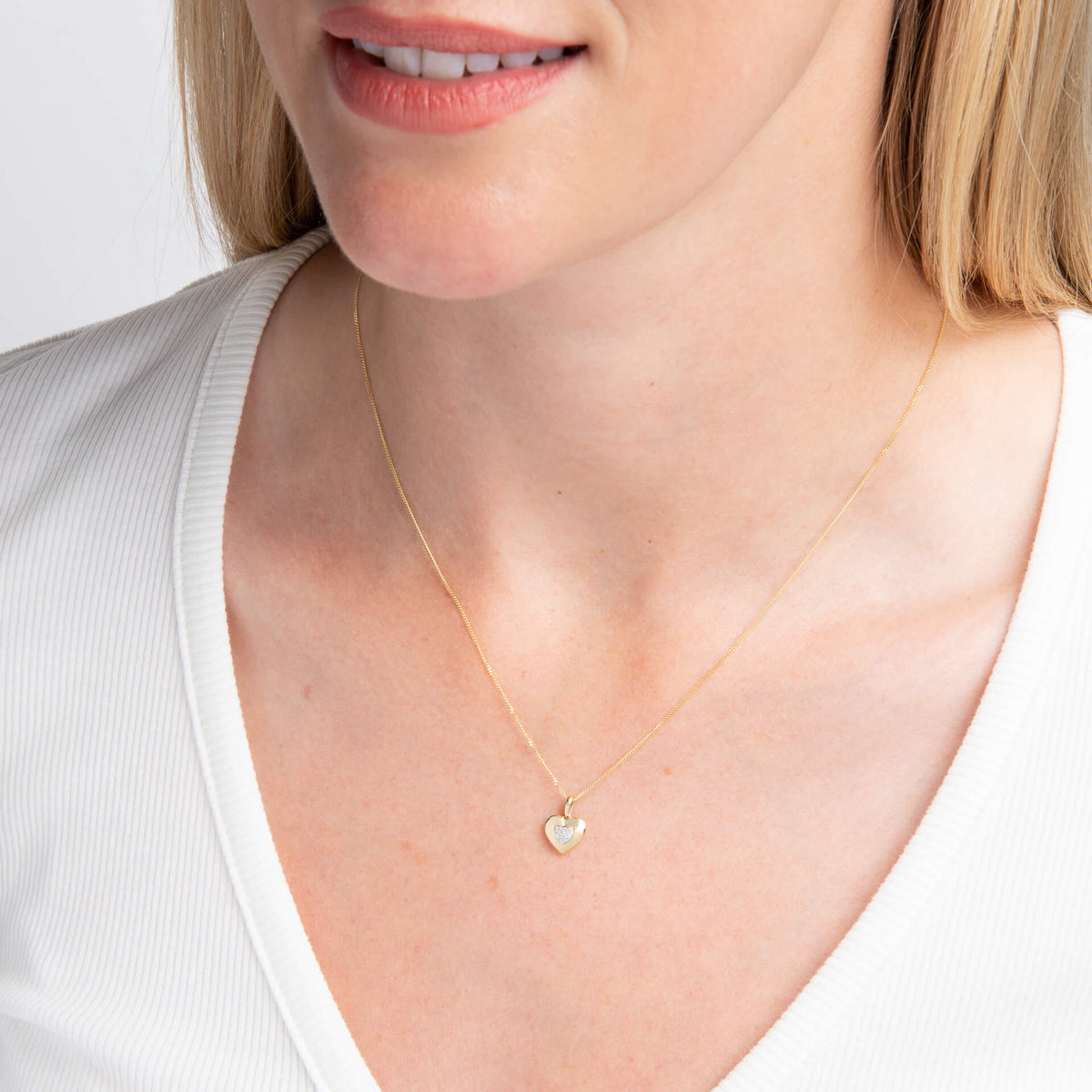 close up woman wearing Gold Pavé Diamond Heart Pendant necklace with white to on white background 