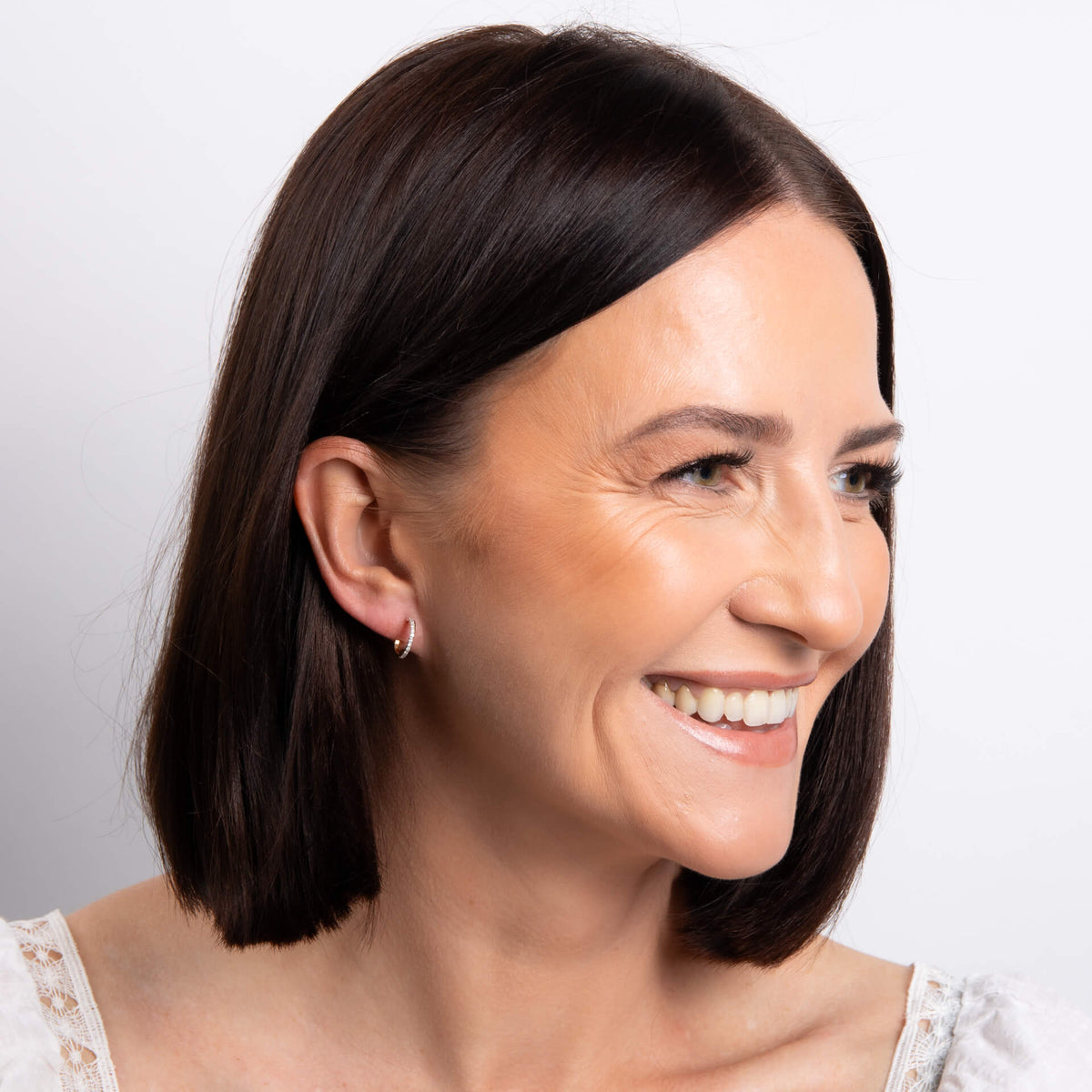 from far woman's ear wearing 9ct Gold Diamond Double Hoop Earrings against white background