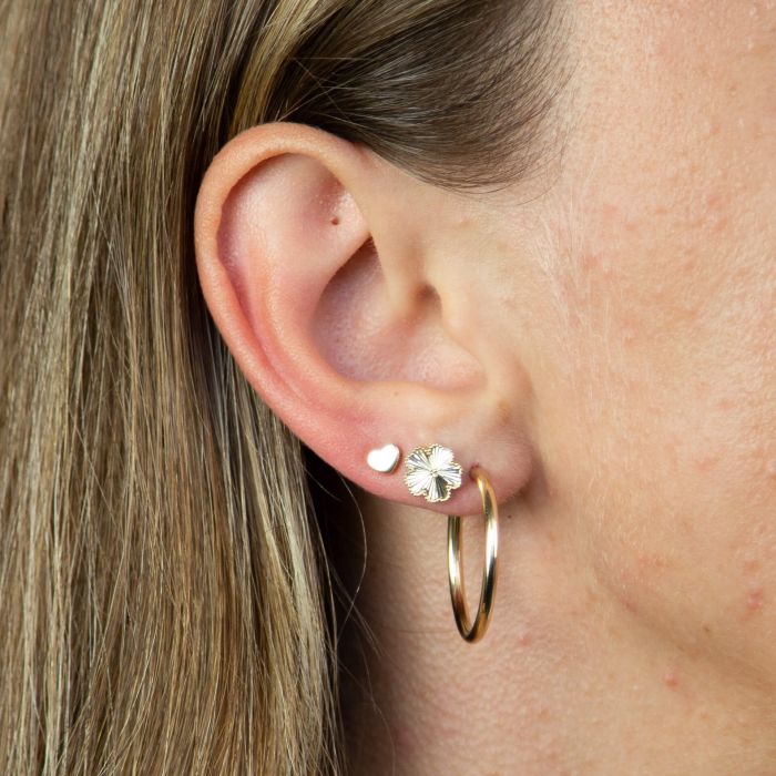 model ear wearing white gold plain heart stud earrings stacked style with  two other earrings. weather worn as a stand alone earring or stacked this studs is great for simple every day wear and durable for just that.