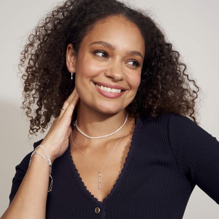 Woman wearing styled Mixed Shapes Long Drop Earrings set and layered with other silverage jewellery items white background