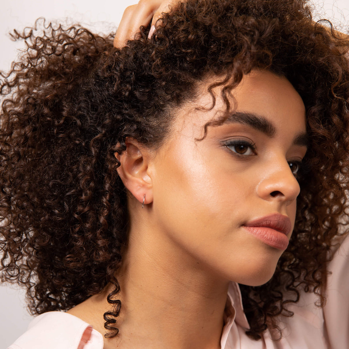 woman showing ear wearing gold slim hoop earring 