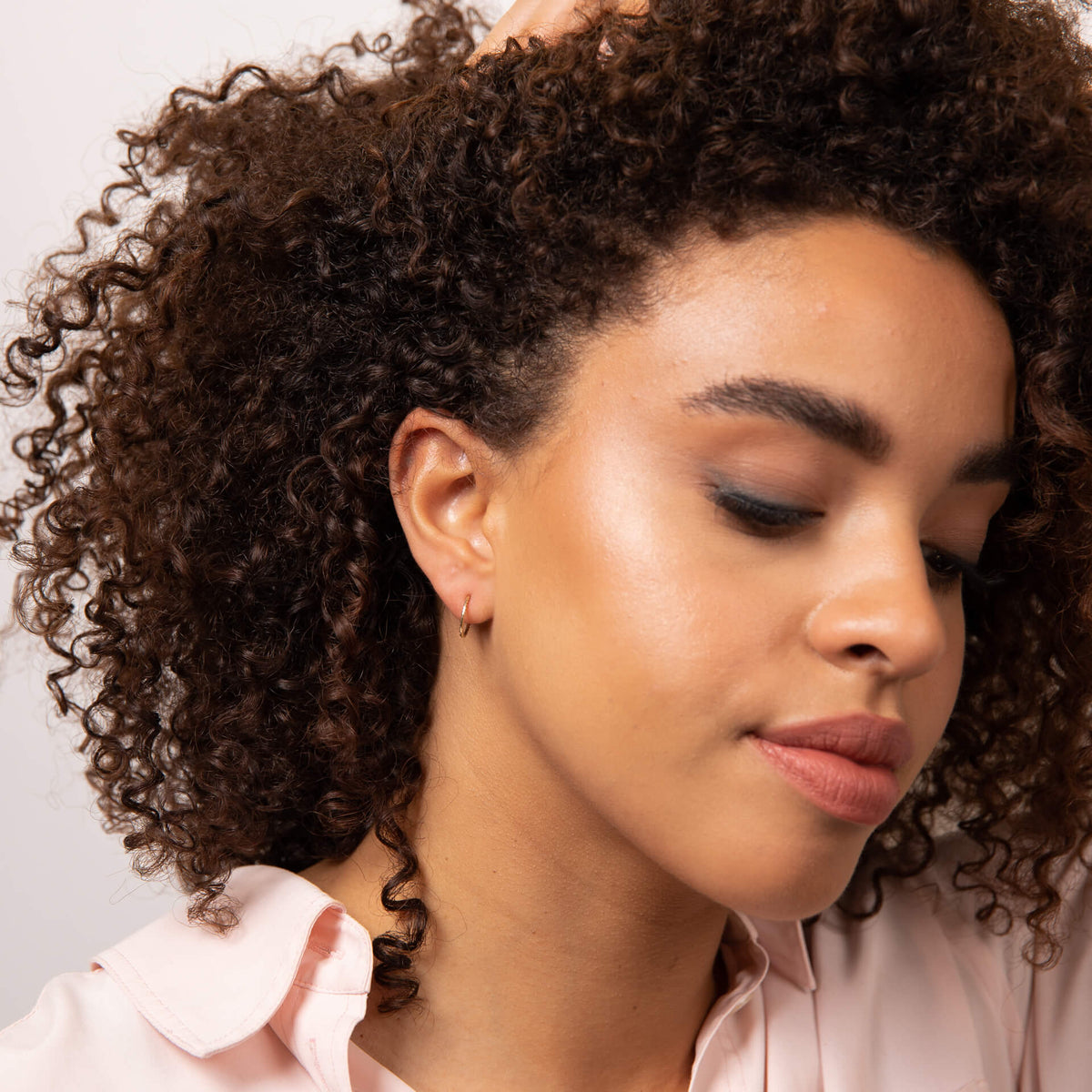 woman wearing gold hoop earring with pink top 
